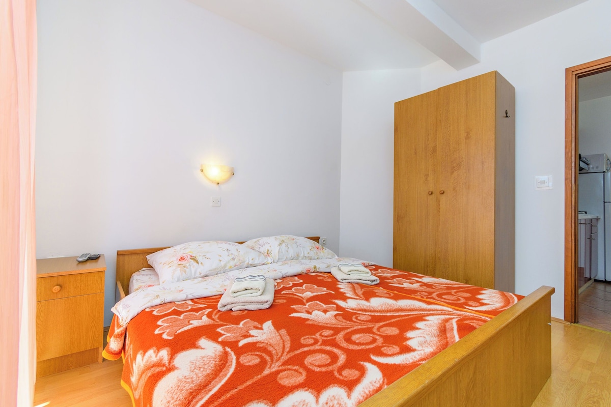 Ein Schlafzimmer mit Bett, Nachttisch, Kleiderschrank und Wandleuchte.