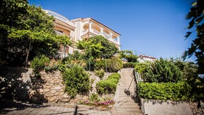 Um edifício de vários andares com fachada de pedra, varanda e escadaria que leva à entrada.