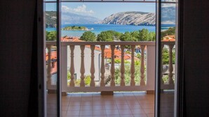 Quarto com varanda e vista panorâmica de um lago e montanhas.