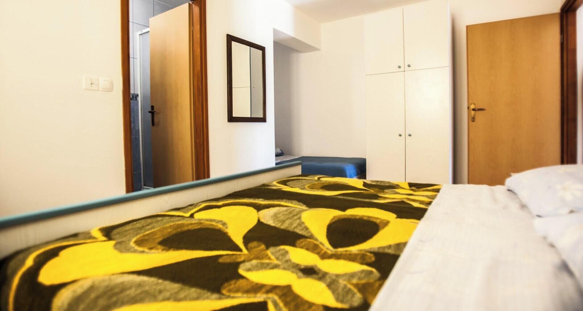 Ein Schlafzimmer mit Bett, Kleiderschrank, Spiegel und Tür.
