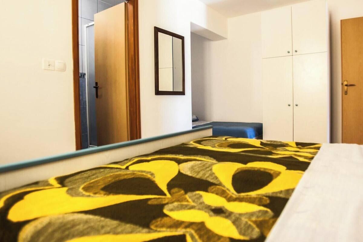A bedroom with a bed, a wardrobe, a mirror, and a door.