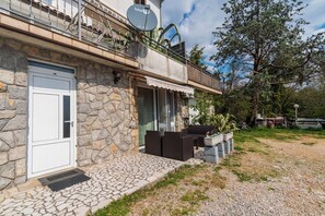 A stone building with a white door, a balcony with outdoor furniture, and a satellite dish. - Apartment Sea View (Opatija)