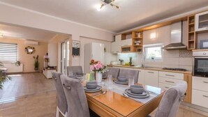 A modern kitchen with white cabinets, a wooden dining table, and grey chairs. - House Rural Blue (Biograd na Moru)