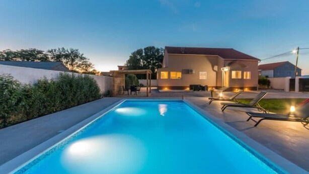 A swimming pool with lounge chairs and a house in the background. - House Rural Blue (Biograd na Moru)