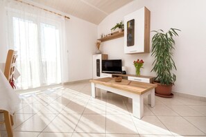 A modern living room with a wooden coffee table, a flat-screen TV, a white cabinet, and a potted plant. - Apartments Skriveni Dvori (Vodice)