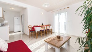 Ein helles Wohnzimmer mit Essbereich, einer Küche und einem großen Fenster.