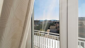 Ein Balkon mit weißer Brüstung, Blick auf eine Wohngegend und einen klaren Himmel.