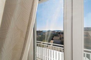 A balcony with a white railing, a view of a residential area, and a clear sky. - Apartments Skriveni Dvori (Vodice)