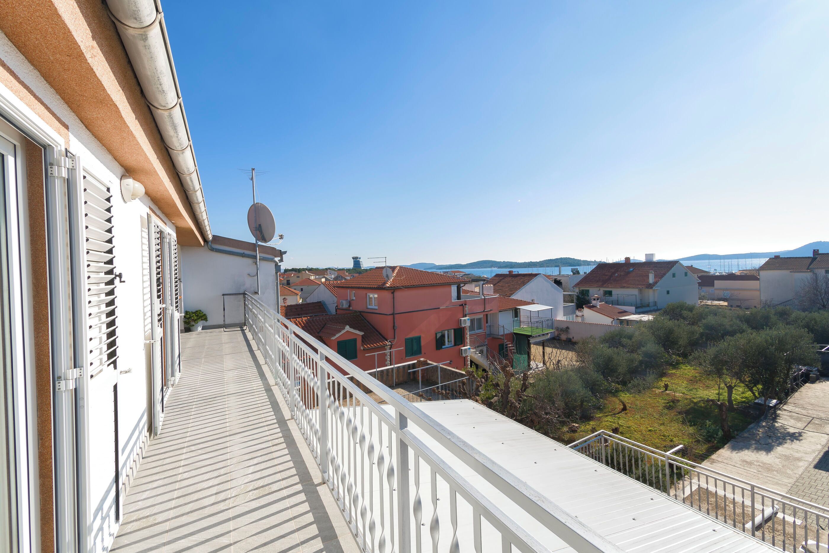 A balcony with a view of a residential area, including houses and a clear sky.