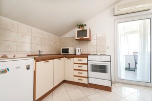 A kitchen with a refrigerator, microwave, oven, and a cabinet with a plant. - Apartments Skriveni Dvori (Vodice)