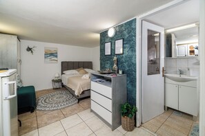 Ein Schlafzimmer mit Bett, Nachttisch, Lampe und einer Wand mit gerahmten Zertifikaten.