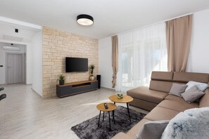Ein modernes Wohnzimmer mit einem Flachbildfernseher an einer Ziegelwand, einem Sofa, einem Couchtisch und einem kleinen Beistelltisch.