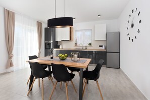 Eine moderne Küche mit Esstisch, Stühlen und einem Kühlschrank.