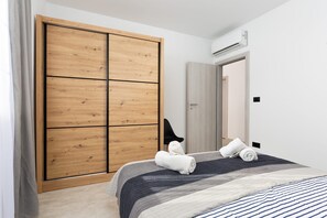 Ein Schlafzimmer mit einem Bett, einem Holzschrank, einer Tür und einer Klimaanlage.