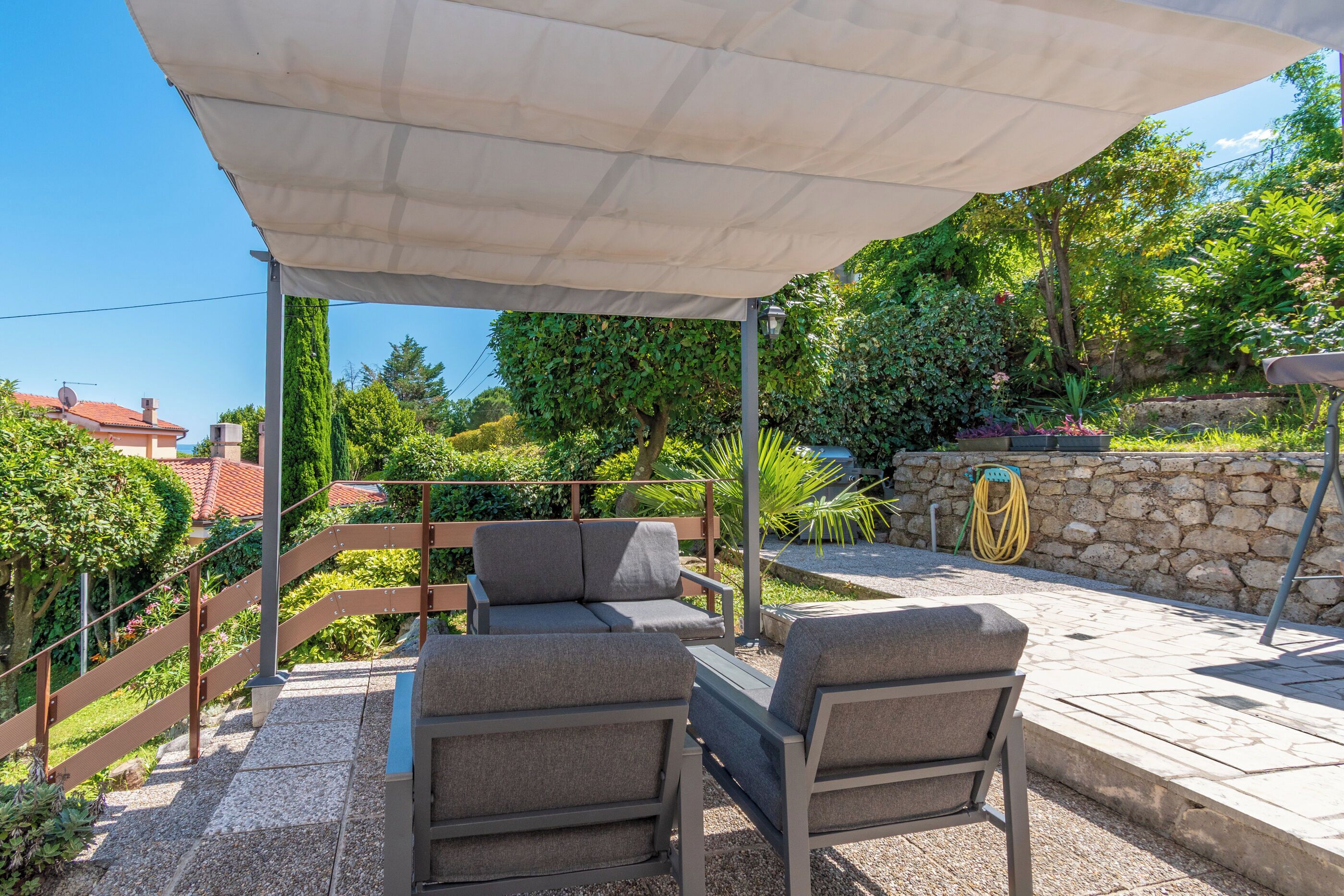 An outdoor patio with a covered seating area, stone steps, and a stone wall.