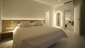 Ein modernes Schlafzimmer mit einem großen Bett, Nachttischen, einer Klimaanlage und einem sichtbaren Badezimmer im Hintergrund.
