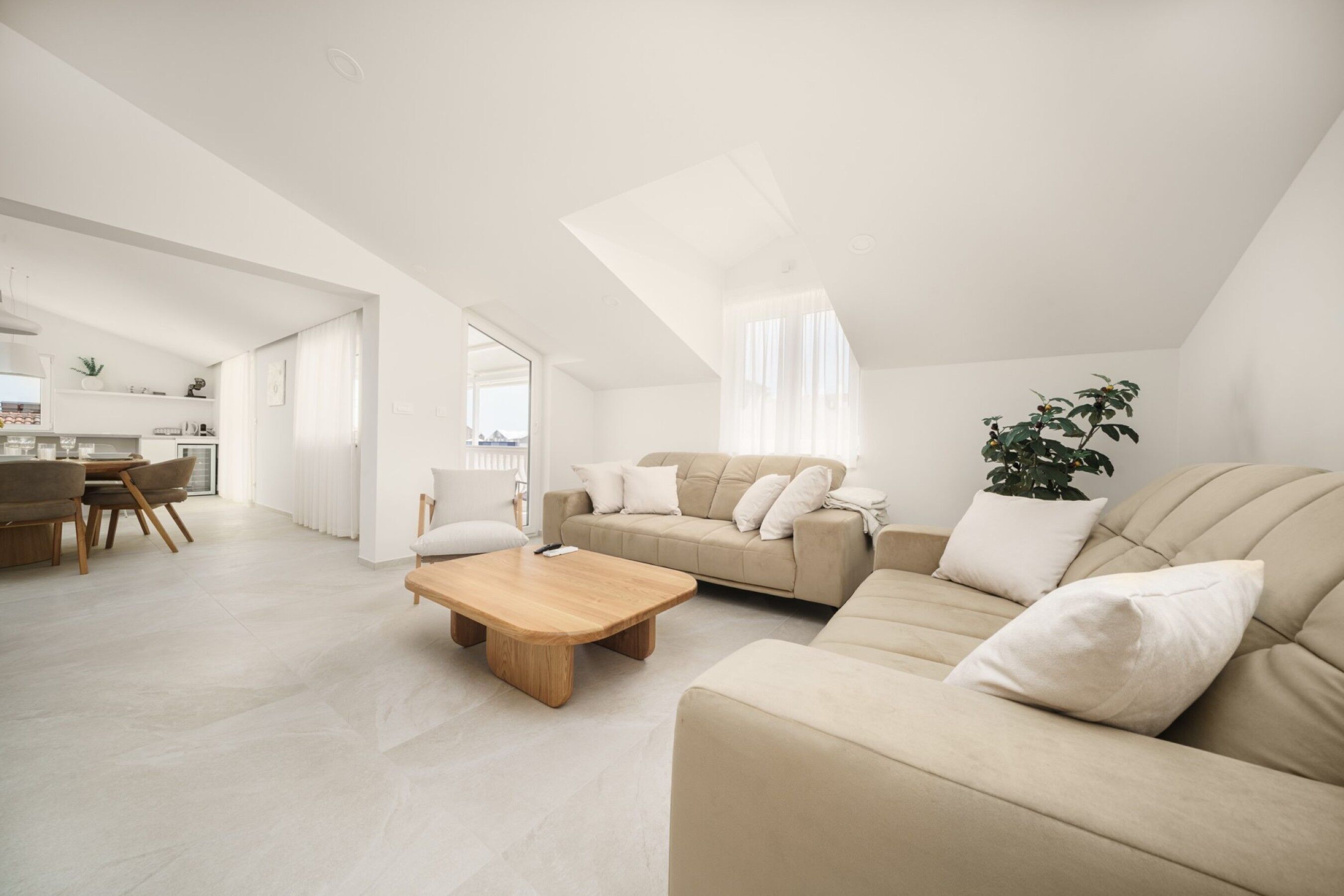 A modern living room with a sofa, coffee table, and dining area.