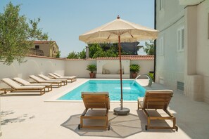 Ein Poolbereich mit Liegestühlen und einem Sonnenschirm.