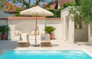 A pool area with two lounge chairs, a white umbrella, and potted plants. - Apartments Bianca Vodice (Vodice)