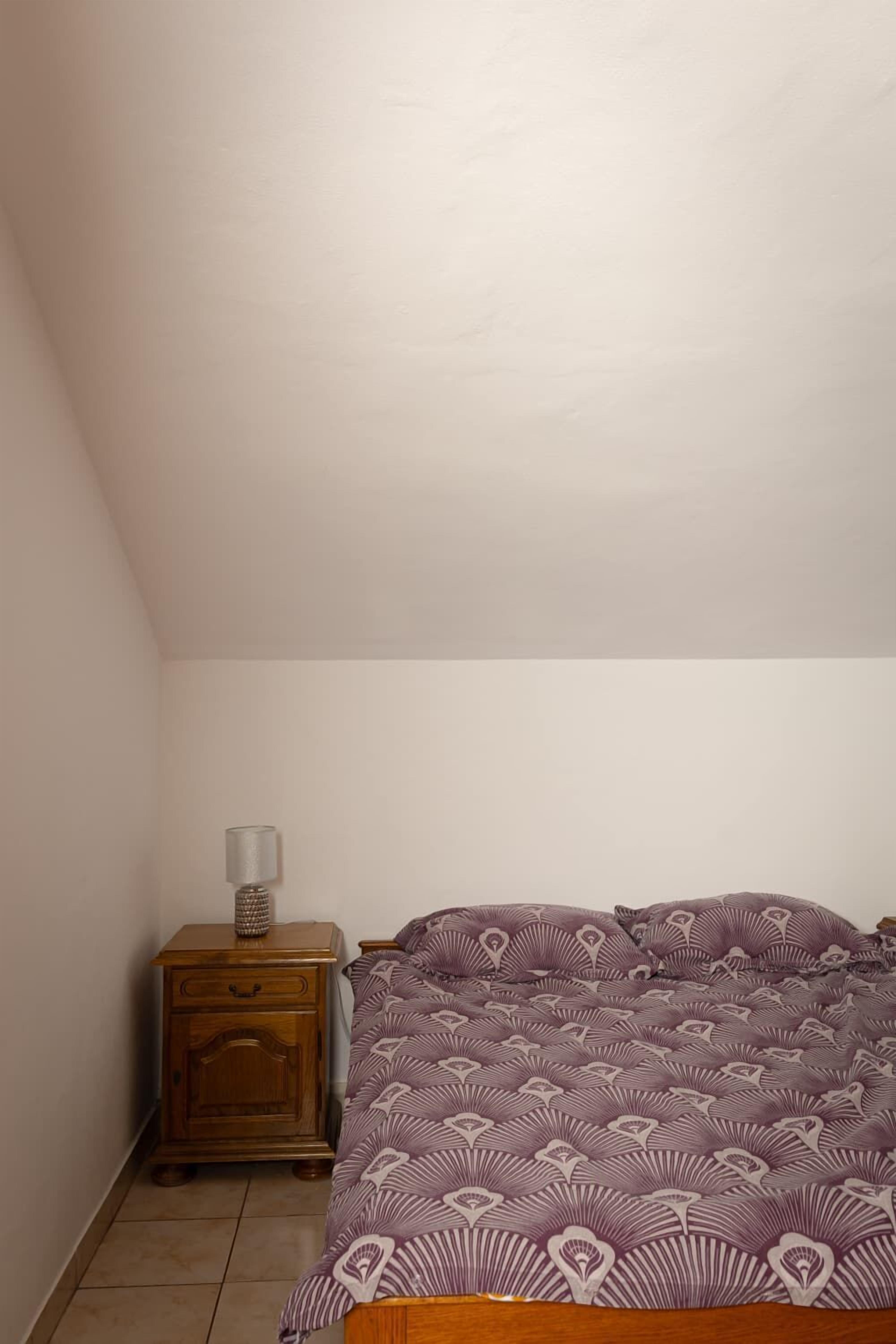 A bedroom with a bed, a nightstand, and a lamp.