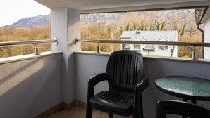 A balcony with a view of mountains, a chair, and a small table. - Apartments Nevistic Lake View (Vinodol)