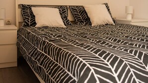 A neatly made bed with a patterned bedspread, a white headboard, and a bedside table with a lamp. - Apartments Nevistic Lake View (Vinodol)