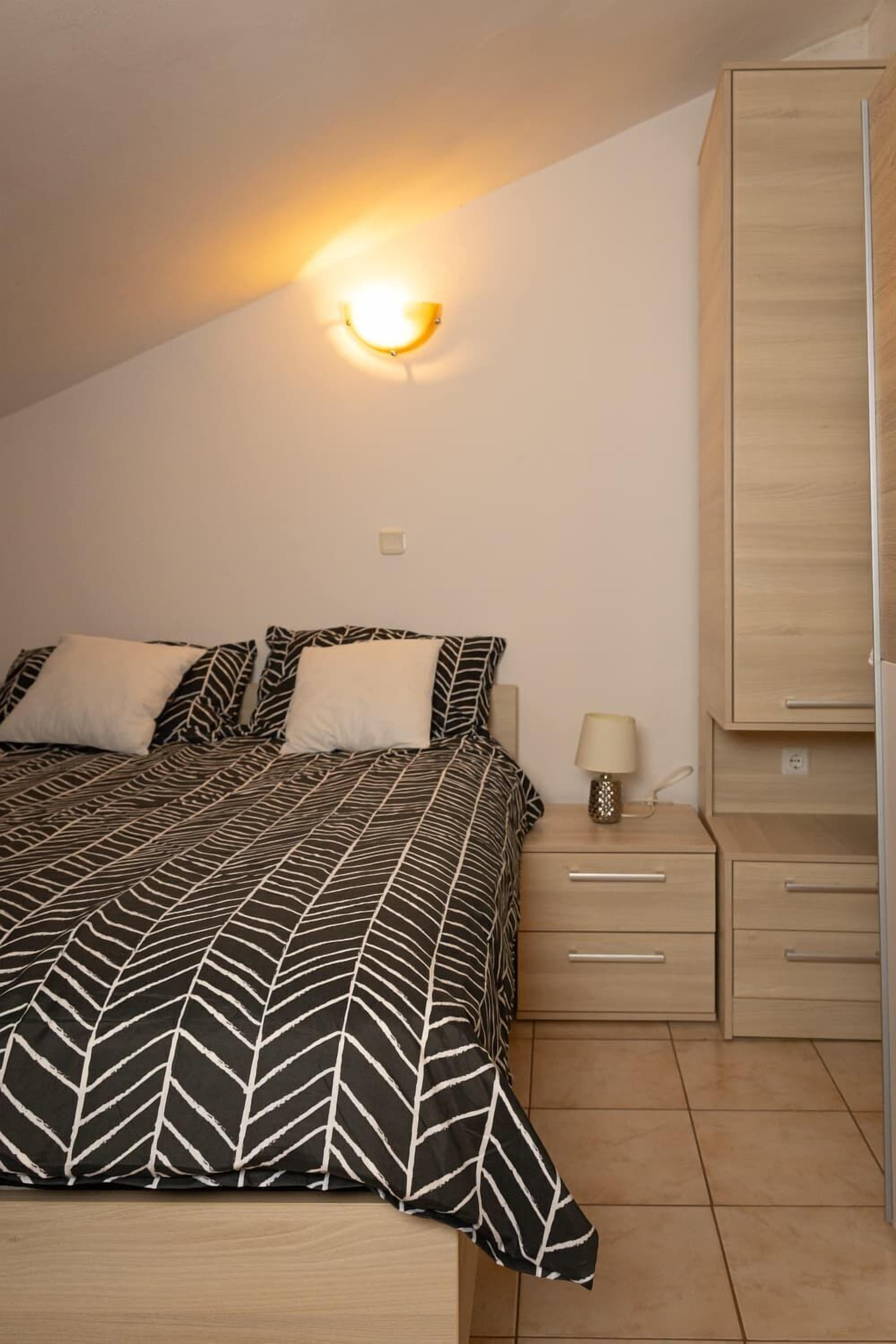 A bedroom with a bed, nightstands, a lamp, and a wardrobe.