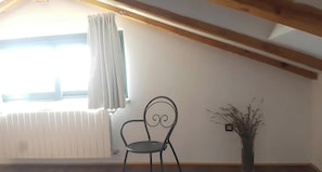 A room with a sloped ceiling, a radiator, a chair, and a vase with plants. - Apartment Adri (Rovinj)