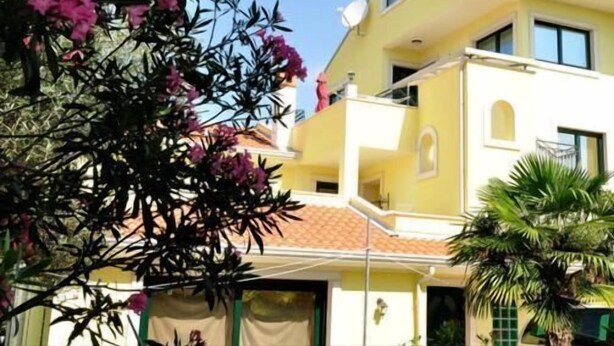 Un bâtiment à deux étages doté d’un balcon, d’une antenne parabolique et d’un toit recouvert de tuiles.