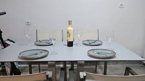 Ett matbord för fyra personer med tillhörande stolar, en flaska champagne och två inramade konstverk på väggen.