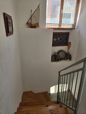 A wooden staircase with a metal railing, a small sailboat model, a framed certificate, and a window with a view. - House Vodice (Vodice)