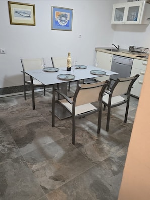 A dining area with a table set for four, chairs, a bottle of champagne, and two framed artworks on the wall. - House Vodice (Vodice)