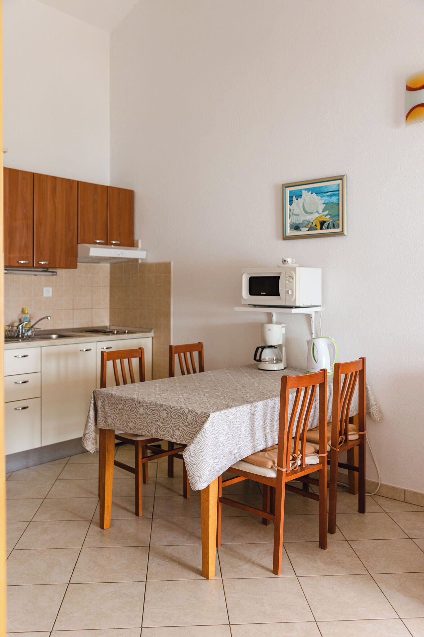 A small kitchen with a dining table, chairs, a microwave, and a coffee maker.