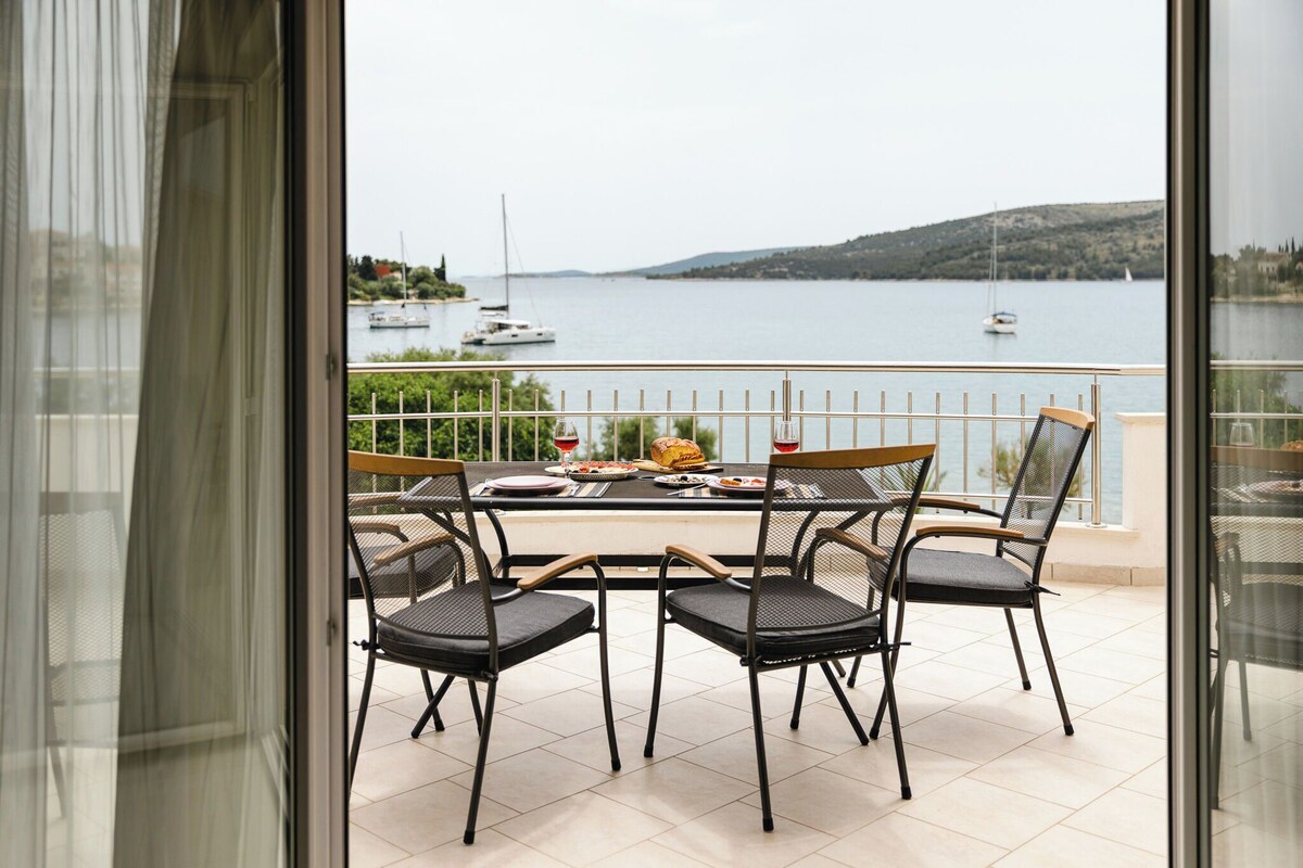 Ein Balkon mit Tisch für zwei Personen mit Blick auf ein Gewässer und Boote.