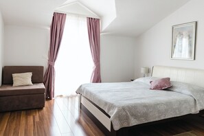 A bedroom with a bed, a sofa, a window with curtains, and a painting on the wall. - Apartments Villa Marija (Seget)