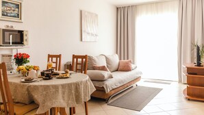 A dining area with a table set for two, a sofa, and a television. - Apartments Villa Marija (Seget)