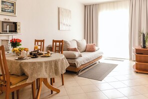 Ein Essbereich mit einem Tisch für zwei Personen, einer Couch und einem Fernseher.