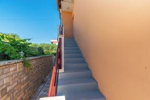 A staircase leading up to a building with a stone wall on one side and a plain wall on the other. - Apartments Andrija (Rab)
