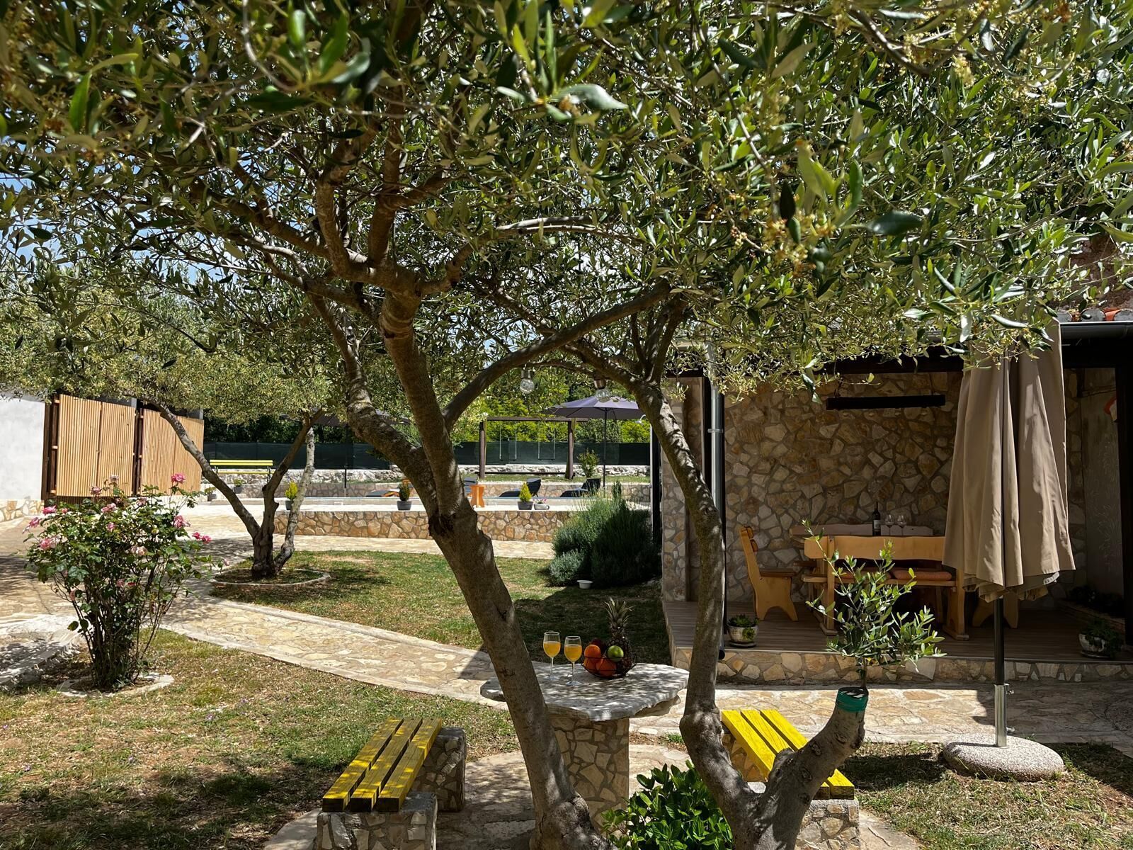 Un espace patio avec une table en pierre, des bancs jaunes et un mur en pierre.