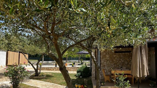 A patio area with a stone table, yellow benches, and a stone wall. - Apartment Feelgood (Benkovac)