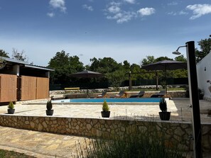 A swimming pool with lounge chairs, a wooden structure, and potted plants. - Apartment Feelgood (Benkovac)