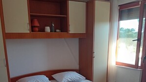 A single bed with white linens, a wooden headboard, and a shelf above. - Apartment Feelgood (Benkovac)