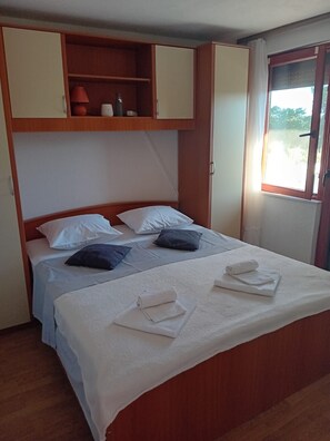 A single bed with white linens, a wooden headboard, and a shelf above. - Apartment Feelgood (Benkovac)