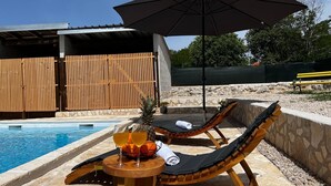 A poolside area with lounge chairs, a table with drinks, and an umbrella. - Apartment Feelgood (Benkovac)