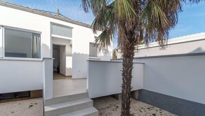 A modern building with a staircase leading to an entrance, a palm tree, and a clear sky. - Apartments Stay Near Paklenica (Starigrad)