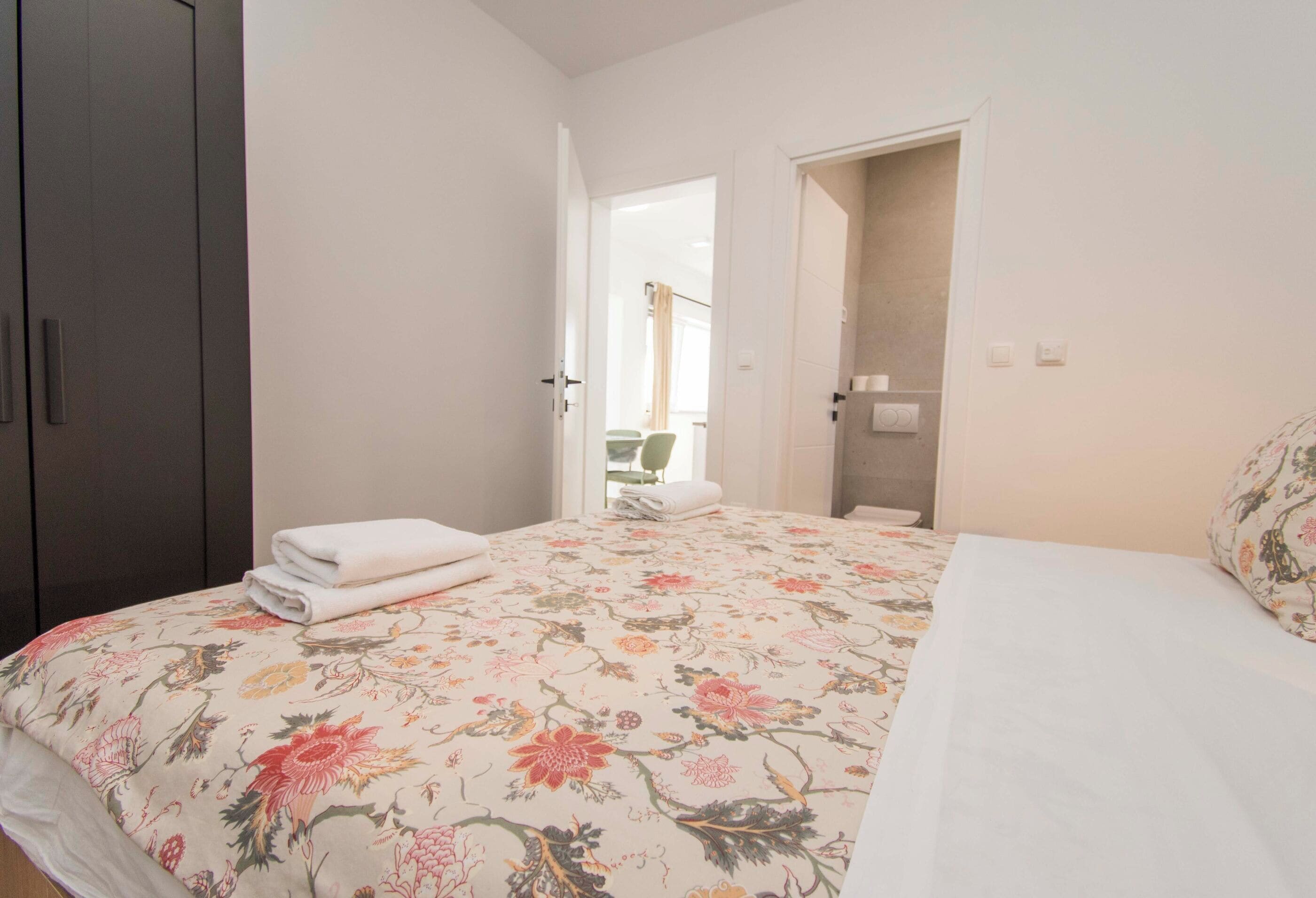 Un dormitorio con cama, armario y baño a la vista a través de una puerta abierta.