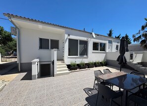 A modern house with a patio, outdoor seating, and potted plants. - Apartments Stay Near Paklenica (Starigrad)