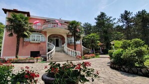 A two-story house with a balcony, a staircase, and a garden with flowers and plants. - Apartment Villa Zizi (Viskovo)