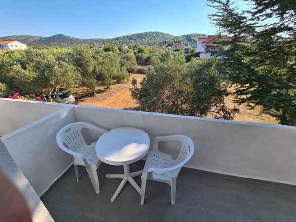 A balcony with two white plastic chairs and a small round table. - House Beachfront Delight (Pasman)