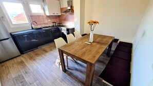 A modern kitchen with black cabinets, a wooden dining table, and a vase with flowers. - House Beachfront Delight (Pasman)